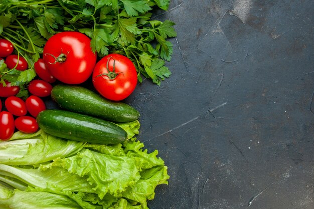 Vista dall'alto verdure fresche prezzemolo pomodori cetrioli lattuga pomodorini sulla superficie scura con copia posto