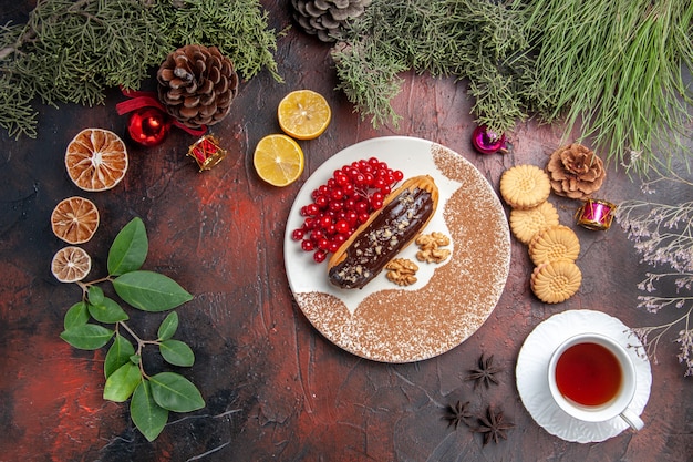 Vista dall'alto yummy choco eclairs con tè e frutti di bosco sul dessert torta torta dolce pavimento scuro