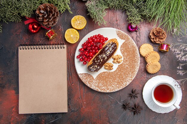 Vista dall'alto yummy choco eclairs con tè e frutti di bosco sul dessert torta torta dolce tavolo scuro