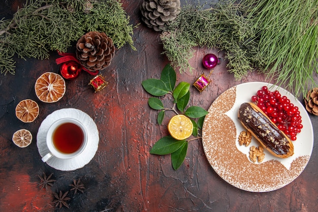 Vista dall'alto yummy choco eclairs con tè e frutti di bosco sul tavolo scuro torta dolce dolce torta