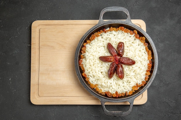 Vista dall'alto yummy plov piatto di riso cotto con uvetta su sfondo scuro piatto di uvetta riso cena olio cibo