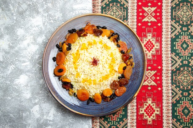 Vista dall'alto yummy shakh plov cotto piatto di riso con uvetta all'interno del piatto sulla scrivania bianca