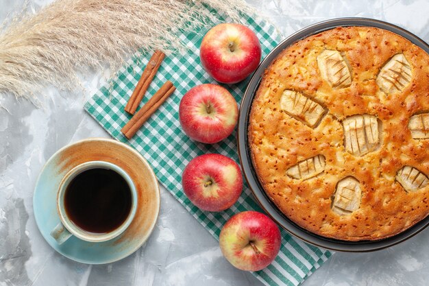 Vista dall'alto yummy torta di mele dolce al forno all'interno della padella con tè e mele sulla scrivania bianca