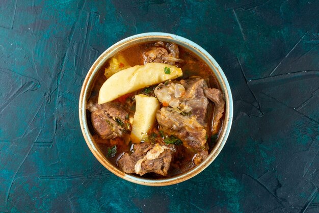 Vista dall'alto zuppa di carne con patate all'interno sul colore blu scuro della cena di cibo vegetale a base di carne