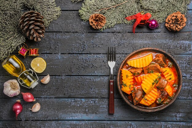 Vista dall'alto zuppa di carne con patate e verdure sulla scrivania scura