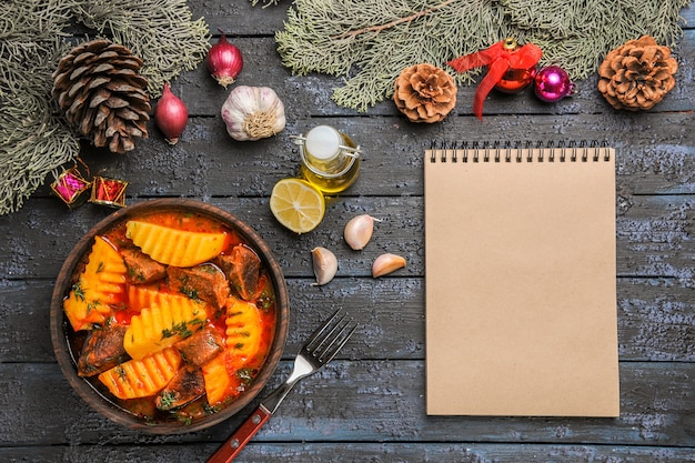 Vista dall'alto zuppa di carne con verdure e patate sulla scrivania buia