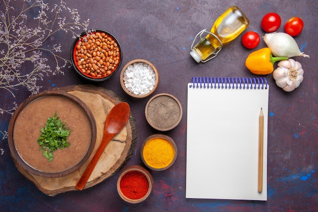 Vista dall'alto zuppa di fagioli marroni deliziosa zuppa cotta con diversi condimenti sul cibo di fagioli pasto zuppa cena scuro scrivania