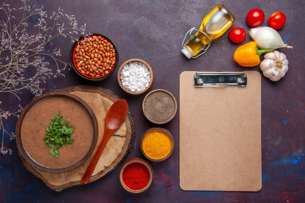 Vista dall'alto zuppa di fagioli marroni deliziosa zuppa cotta con diversi condimenti sul cibo di fagioli pasto zuppa cena superficie scura