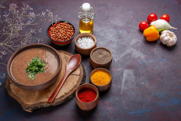 Vista dall'alto zuppa di fagioli marroni deliziosa zuppa cotta con diversi condimenti sul pavimento scuro cena zuppa di fagioli cibo pasto