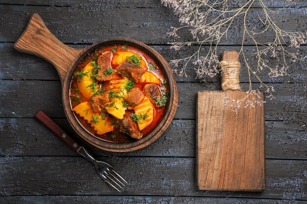 Vista dall'alto zuppa di ragù di carne con verdure e patate sulla scrivania scura