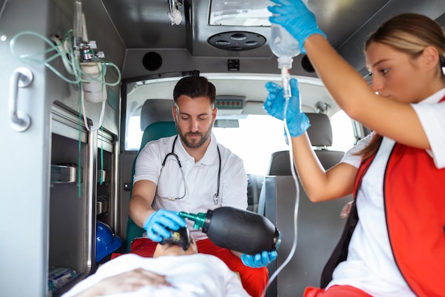 Vista dall'interno dell'ambulanza degli operatori dei servizi di emergenza in uniforme che si prendono cura del paziente sulla barella durante la pandemia di coronavirus