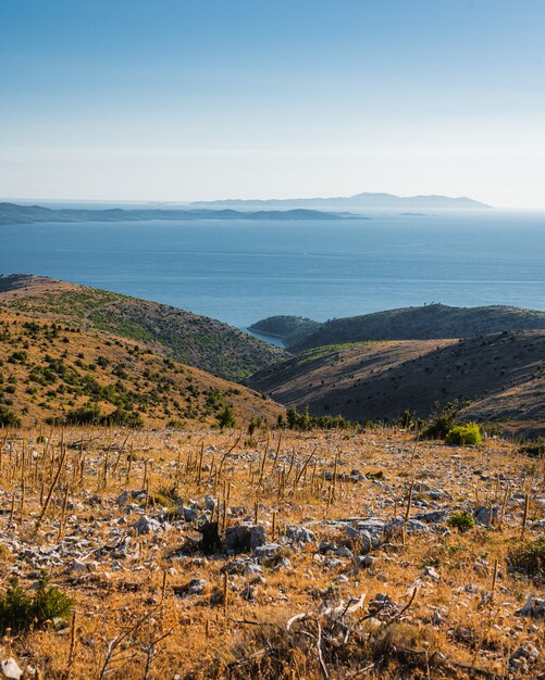 Vista del paesaggio delle colline sulla riva di un lago calmo sotto il cielo blu