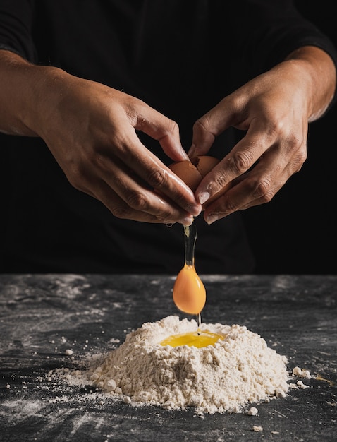 Vista del primo piano che mescola uovo con farina per la composizione nella pasta