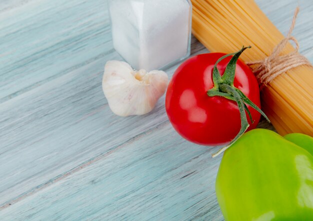 Vista del primo piano dei maccheroni dei vermicelli con l'aglio e il sale del pepe del pomodoro sulla tavola di legno