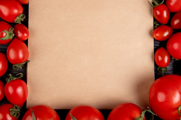 Vista del primo piano dei pomodori intorno al blocco note sulla tavola di legno con lo spazio della copia