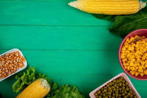 Vista del primo piano dei semi del cereale in cucchiaio con gli spinaci della lattuga dei semi su fondo verde con lo spazio della copia