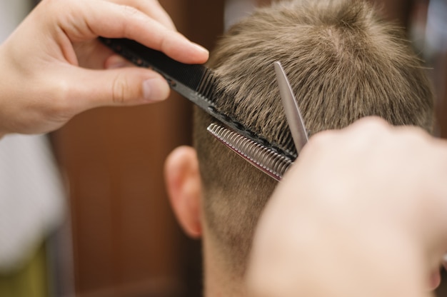 Vista del primo piano del parrucchiere che dà un taglio di capelli ad un cliente