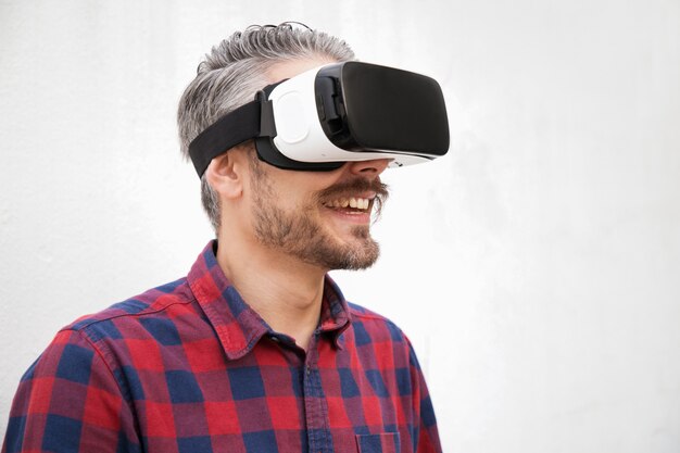 Vista del primo piano dell'uomo allegro in cuffia avricolare di VR