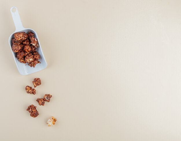 Vista del primo piano della cucchiaiata di popcorn del cioccolato dalla parte di sinistra e del fondo bianco con lo spazio della copia
