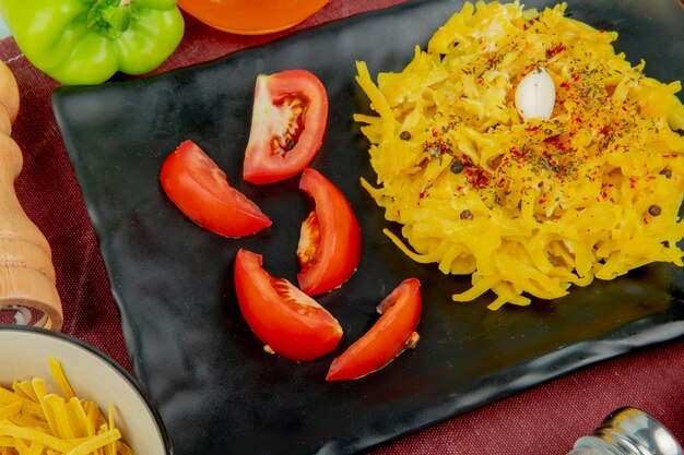 Vista del primo piano della pasta dei maccheroni e del pomodoro affettato in zolla con il sale dei maccheroni di tagliatelle del pepe sul panno di bordo