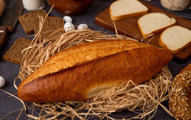 Vista del primo piano delle baguette vietnamite sulla superficie della paglia con differenti pani su fondo marrone rossiccio