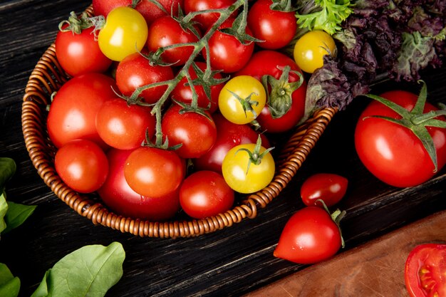 Vista del primo piano delle verdure come merce nel carrello del coriandolo del basilico del pomodoro con spinaci sulla tavola di legno