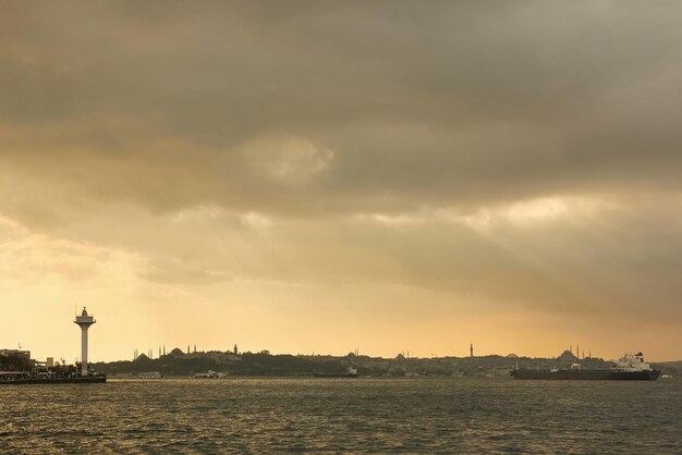 Vista del vecchio edificio storico con moschee torri edifici in stile orientale navi da carico rimorchiatori nel porto sulla rada sullo sfondo del cielo nuvoloso