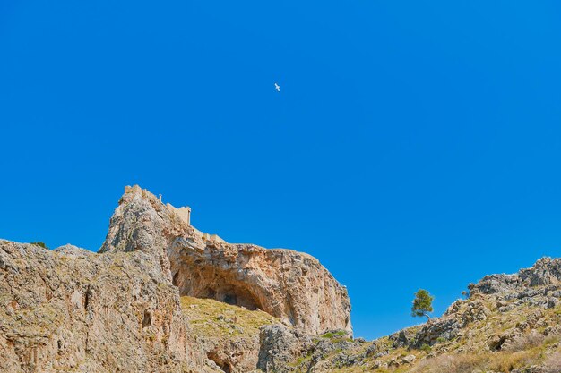 Vista dell'acropoli e delle grotte della città di Lindos dal lato della baia di St Paul's Bay cielo blu chiaro isola di Rodi isole greche dell'arcipelago del Dodecaneso Vacanze e viaggi