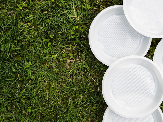 Vista dell'angolo alto del piatto vuoto di plastica bianco su erba