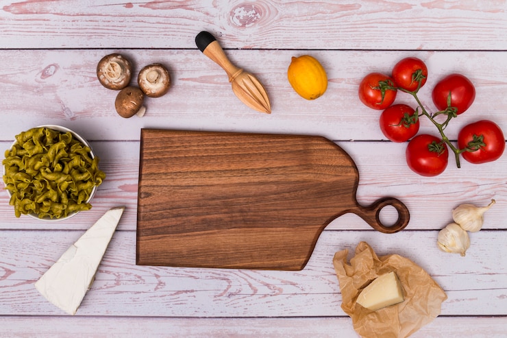 Foto gratuito vista dell'angolo alto del tagliere di legno che circonda dalla pasta cruda e dall'ingrediente sulla tavola