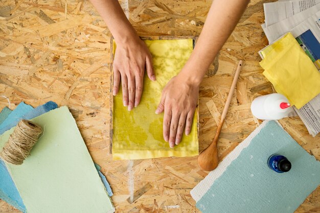 Vista dell&#39;angolo alto della polpa di carta della copertura della mano di una femmina con il panno giallo