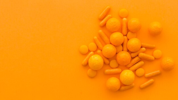 Vista dell&#39;angolo alto delle caramelle di forma della capsula e di circolare su fondo arancio
