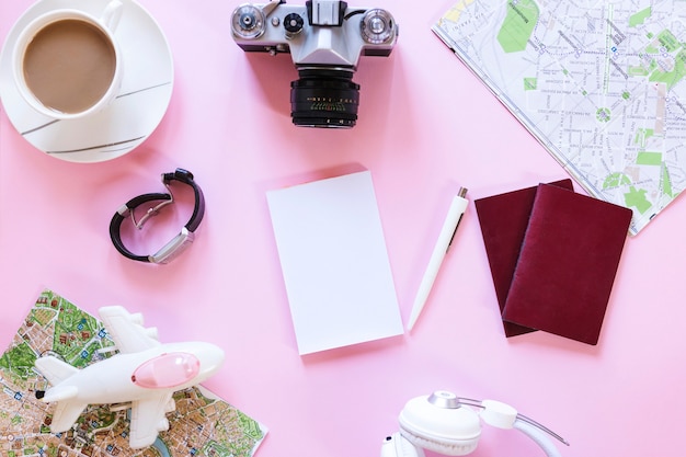 Vista dell&#39;angolo alto di vari accessori del viaggiatore con la tazza di tè su fondo rosa