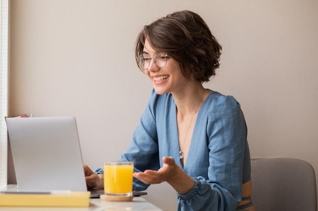 Vista della donna che sorride sul computer portatile a casa