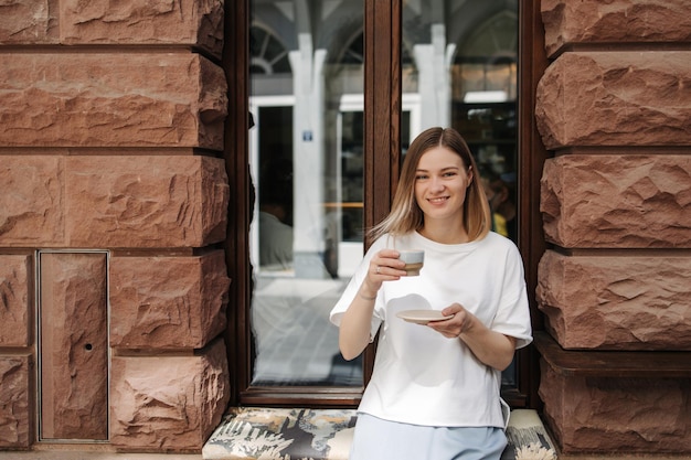 Vista della giovane donna che tiene tazza di caffè e sorriso