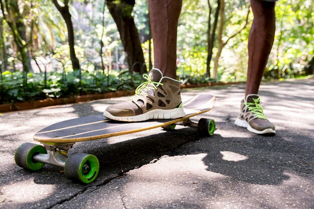 Vista di angolo basso dei piedi di un giovane skateboarder maschio in scarpe da ginnastica al parco