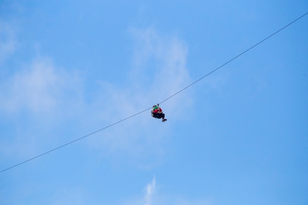 Vista di angolo basso del turista che guida un'avventura della linea zip contro il cielo blu