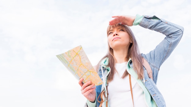 Vista di angolo basso di un viaggiatore femminile che la protegge occhi contro il cielo