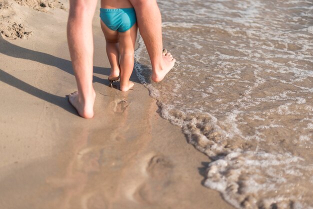 Vista di colpo medio di padre e figlio che camminano sulla spiaggia