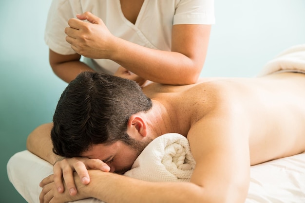 Vista di profilo di un giovane che riceve un massaggio lomi lomi in una clinica termale