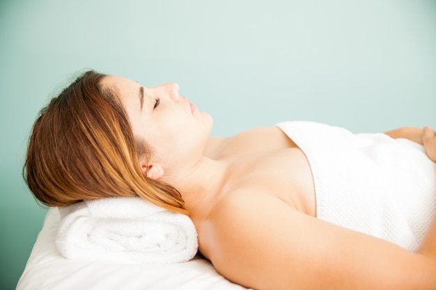 Vista di profilo di una bella giovane bruna che si addormenta dopo un massaggio rilassante in una clinica e spa