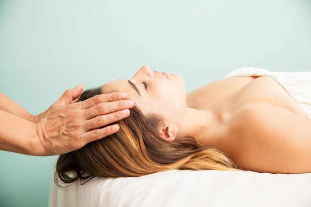 Vista di profilo di una giovane donna carina che ottiene la sua energia equilibrata in una sessione di reiki in una clinica e spa