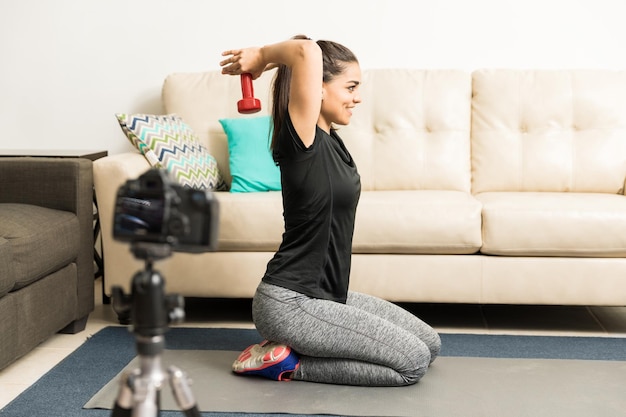 Vista di profilo di una giovane donna in abito sportivo che registra un video per il suo blog di fitness