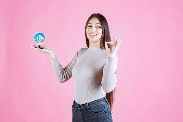 Vista di profilo di una ragazza che tiene un mini globo con fiducia