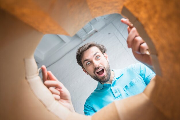 Vista di sezione bassa di un uomo sorpreso che osserva all&#39;interno del sacco di carta