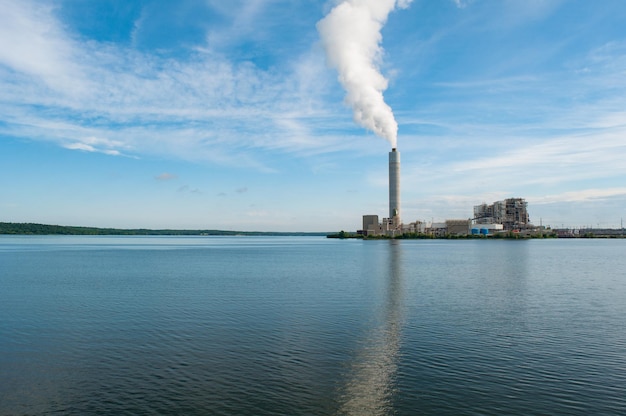 Vista di un'intensa colonna di fumo che esce dal waterscape del tubo della fabbrica in primo piano