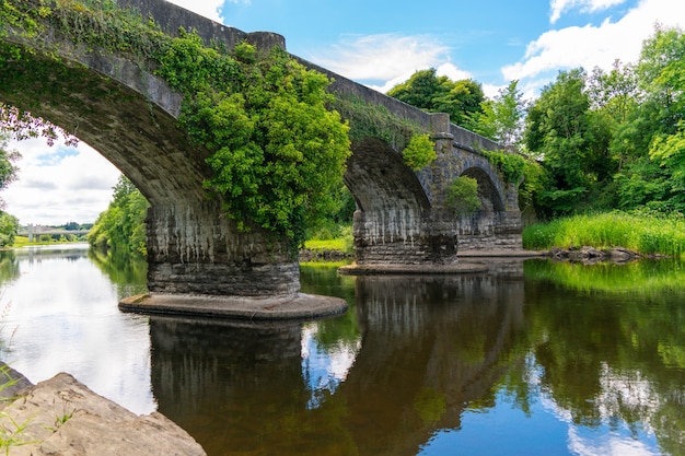 Vista di un vecchio ponte ad arco con il suo riflesso sul fiume