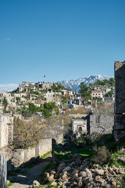 Vista di una città abbandonata vicino al villaggio di Kayakoy e montagne innevate Città fantasma abbandonata Karmilisos in inverno a Fethiye Turchia rovine di case in pietra Sito dell'antica città greca