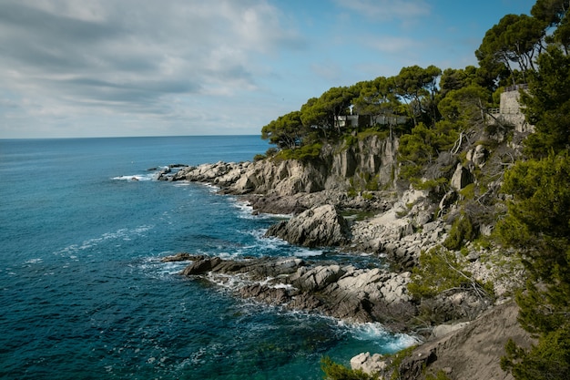 Vista di una spiaggia rocciosa con un cielo blu nuvoloso