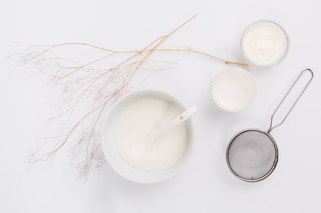 Vista elevata del latte; zucchero e utensili da cucina con ramoscello